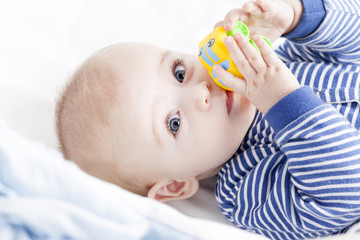 Baby with blue eyes playing with a toy