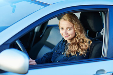 Young confident woman driving a car