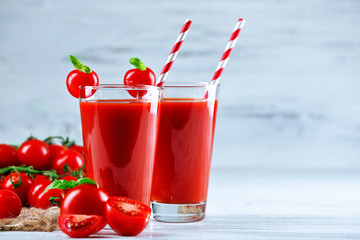 Glasses of tomato juice with vegetables on wooden table background