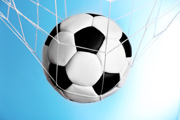 Soccer ball in the net on blue background
