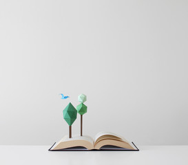 Trees and bird growing out of an open pop-up book