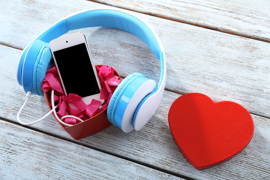 blue headphones with heart and phone on wooden background