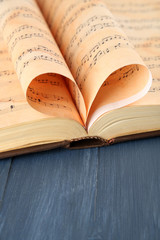 Book pages curved into heart shape on table close up