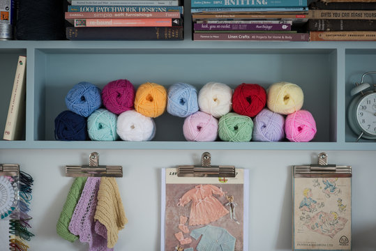 Yarn and Knitting Books Organized on Shelf Over Clipboards