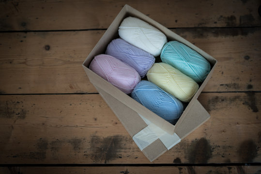 Box of Assorted Color Yarn on Wooden Surface