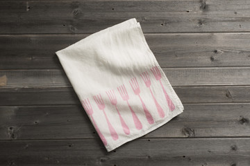 Folded Napkin with Pink Fork Pattern on Wooden Surface