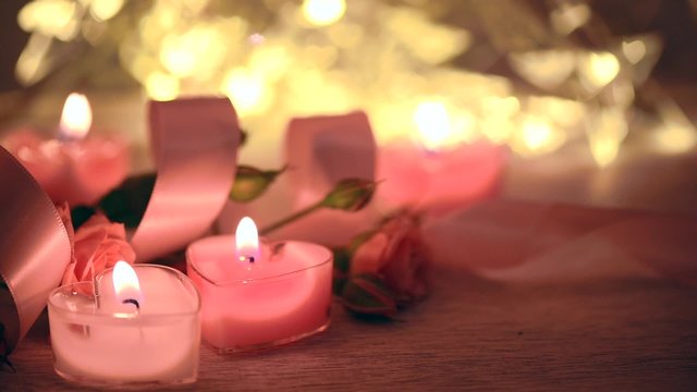 Pink burning candles and brunch of roses on beautiful scene. Valentine's day