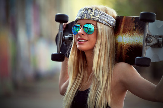 Young woman with skating board on painted wall background