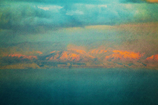 Textured vintage image of glowing mountains over sea