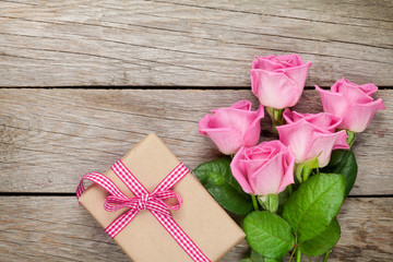 Pink roses and valentines day gift box over wooden table