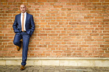 Fototapeta na wymiar Young fashionable men in a suit against brick wall
