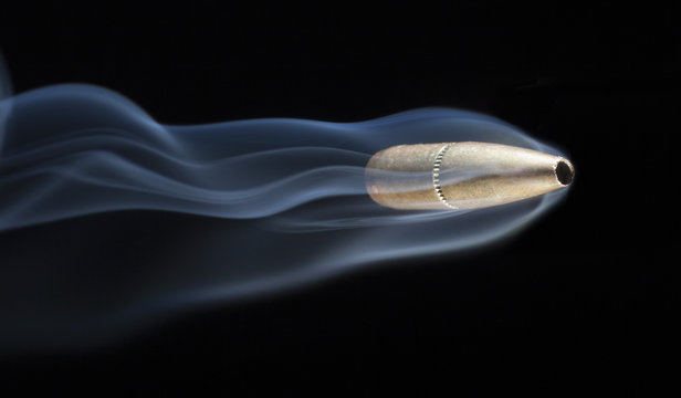 Speeding bullet with smoke behind after a shooting on a black background
