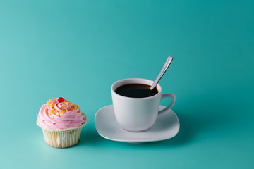 colorful pink cupcake on aquamarine background with coffee cup