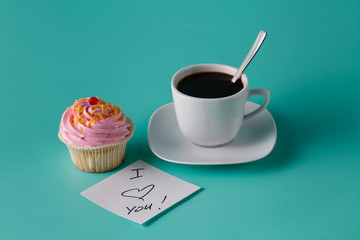 colorful pink cupcake on aquamarine background with coffee cup