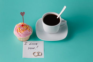 colorful pink cupcake on aquamarine background with coffee cup