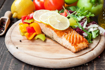 Fried salmon with vegetables on a wooden table