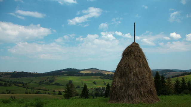 4K Timelapse of clouds and haystack on green field
