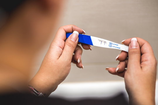 Junge Frau hält Schwangerschaftstest in Händen