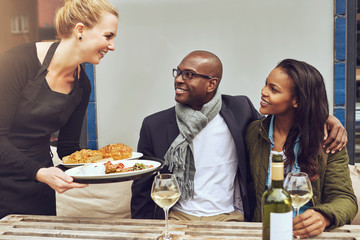 Waitress serving an African American couple dinner