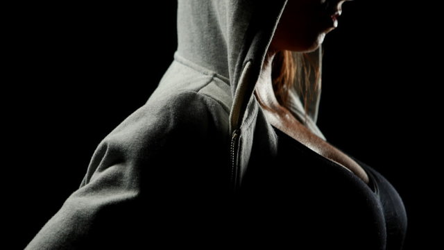 Muscular woman wearing grey hood