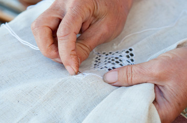 Senior Woman knitting a white fabric cloth