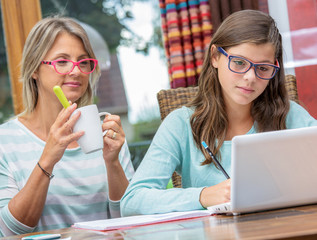 smiling teen girl doing homework with a blond teacher