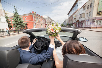Newlywed couple is driving a convertible
