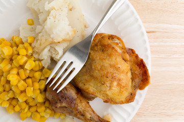 Chicken, corn and mashed potatoes on paper plate with fork