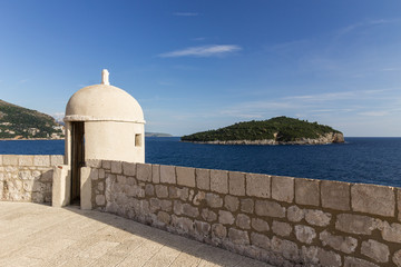View of a small tower at the city walls and Lokrum Island in Dubrovnik, Croatia.