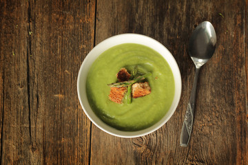 Top view of a asparagus soup with spoon in a white bowl