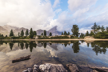 Fascinating reflections of the Dolomites mountains in lake Limedes at Sunset. Vivid and bright colors of the dramatic evening.
