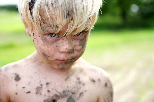Sad Young Boy Covered in Dirt and Mud Outside - Powered by Adobe