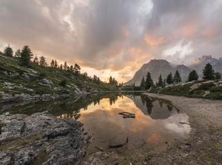 Fascinating reflections of the Dolomites mountains in lake Limedes at Sunset. Vivid and bright colors of the dramatic evening.