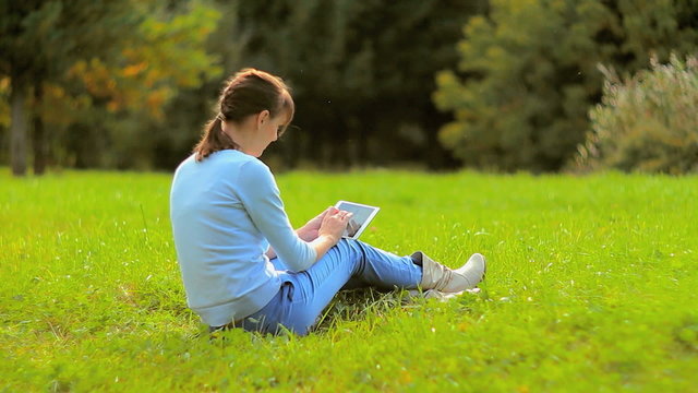 Young woman using tablet computer touchscreen in park 