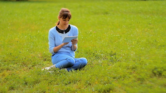 Young woman using tablet computer touchscreen in park 