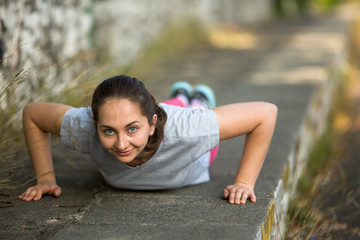 Young sports girl doing push-ups during the warm-up before Jogging in the Park. Healthy lifestyle.