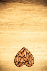 Heart shaped almonds on wooden surface background