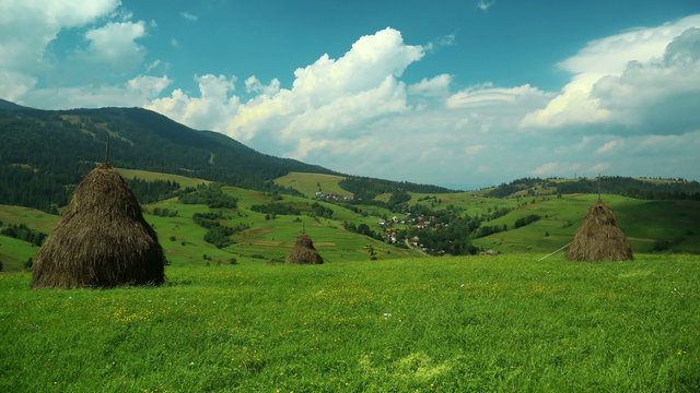 4K Timelapse of clouds and beautiful green fields with haystacks