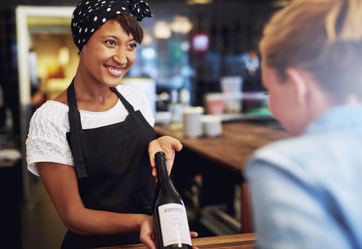 Smiling waitress or bartender showing red wine