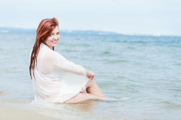 Fototapeta na wymiar Sensual girl wet cloth in water on the coast.