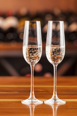 two glass of champagne in background with bottles of wine