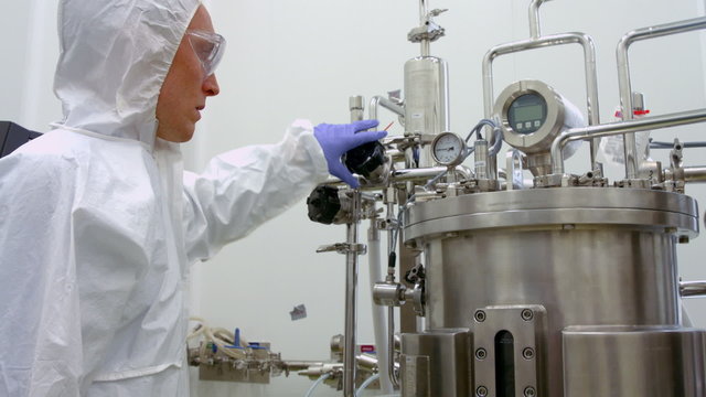 Scientist in protective suits working on vat