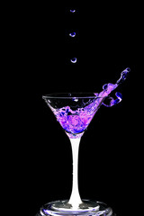 Cocktail glass with splashes on a black background.