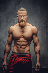 Fototapeta na wymiar Muscular man with beard posing over grey background.