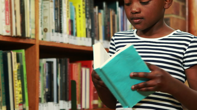 Little girl reading book in library