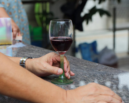 Asian man's hand holding a glass red wine