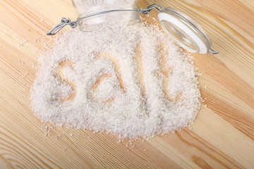 spilling sea salt in glass jar on wooden background