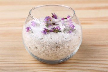 Fototapeta na wymiar sea salt in bowl with flowers on wooden background