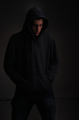 Naklejka na ściany i meble teenager with hoodie looking down on black background