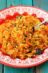 Homemade vegan pumpkin pilaf in red plate with white fork on tur